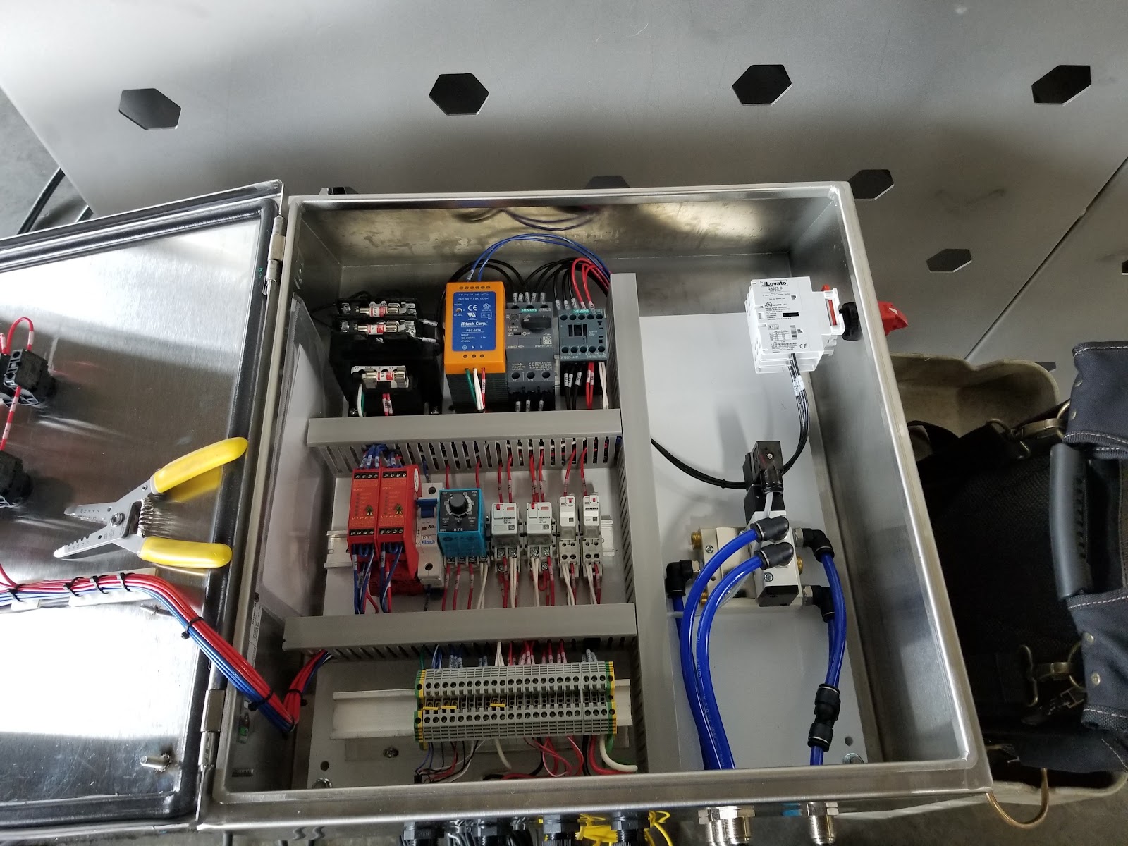 Open stainless enclosure with power supplies, starters, and terminal blocks.