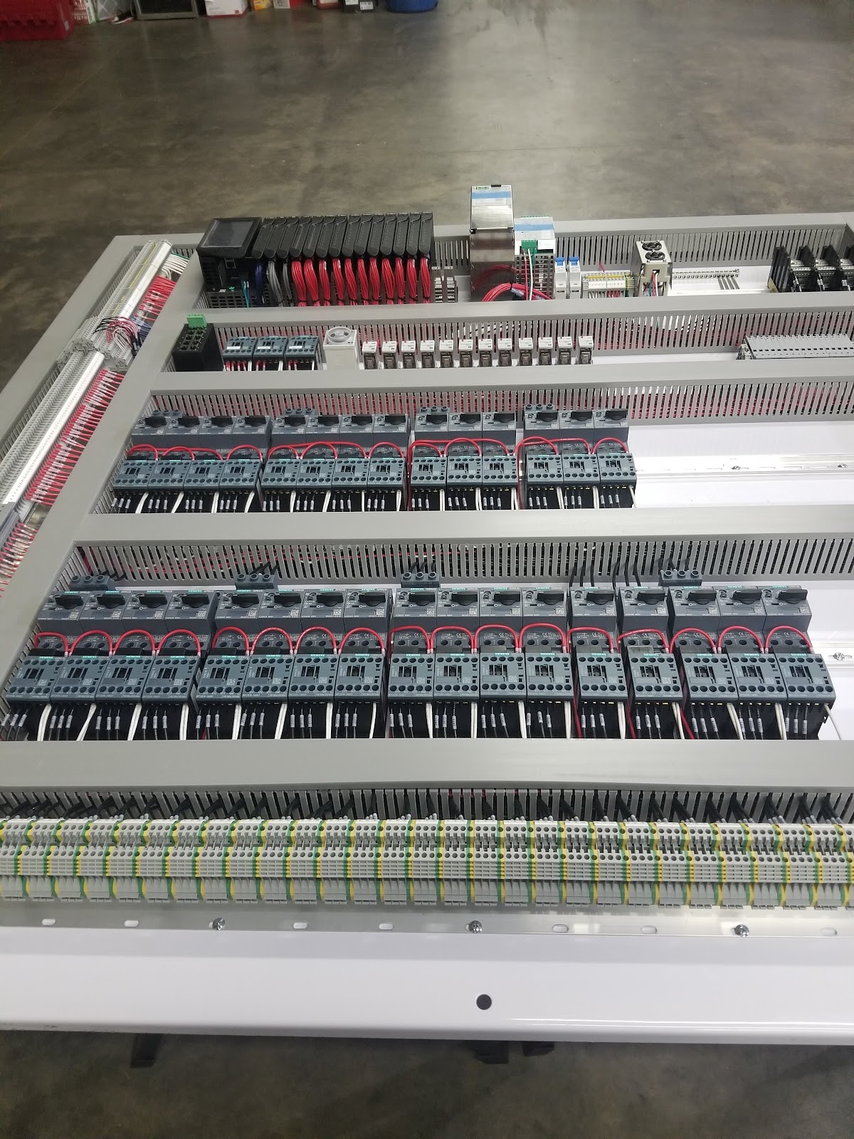 Large gray control enclosure with PLC, motor starters, and terminal blocks.