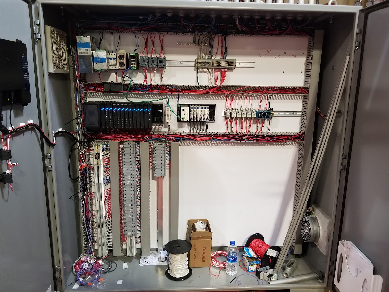 Open gray cabinet with wiring channels and mounted components.