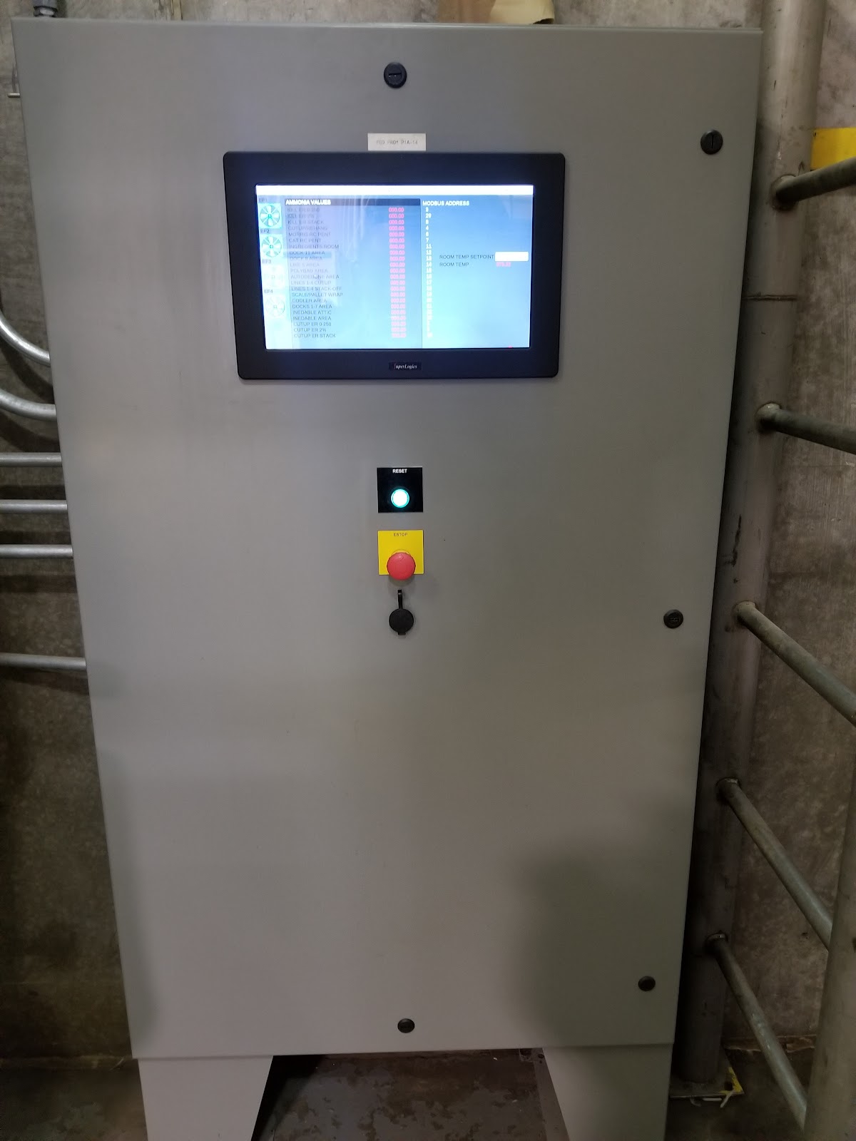 Tall gray cabinet with a centered HMI and red emergency stop.