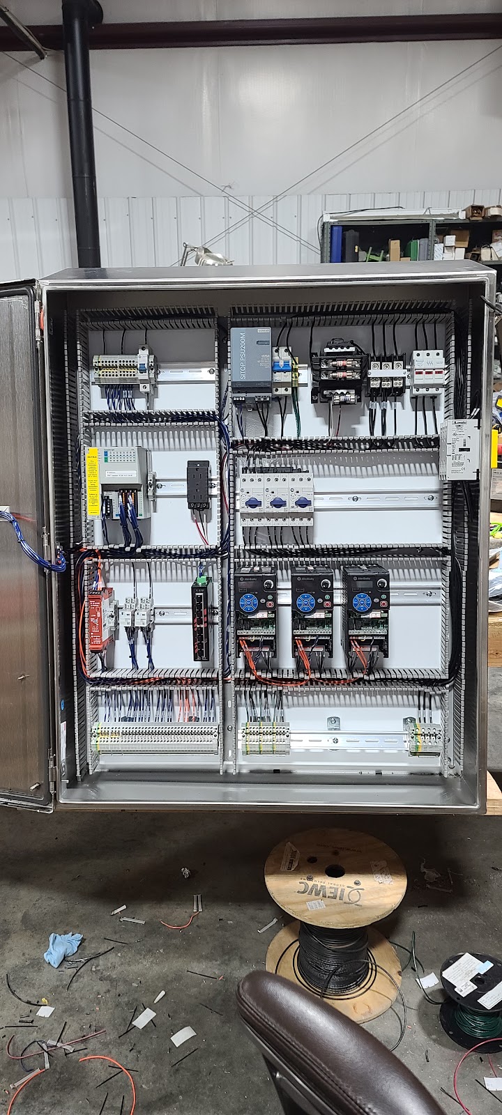 Open control cabinet with relays, breakers, and dense wiring.