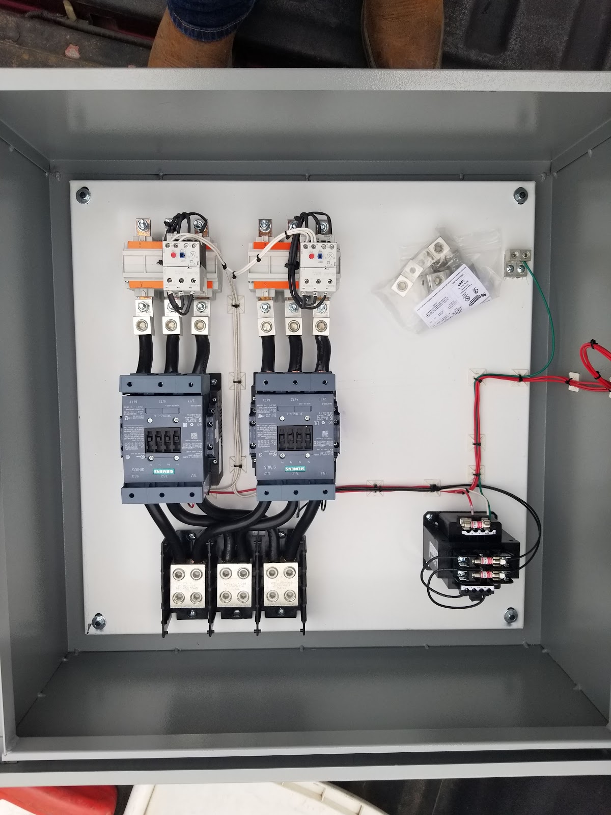 Small open electrical box with breakers and terminal blocks.
