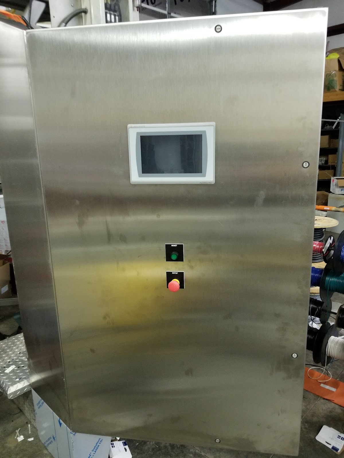 Tall stainless cabinet with a PanelView, Reset, and emergency stop.