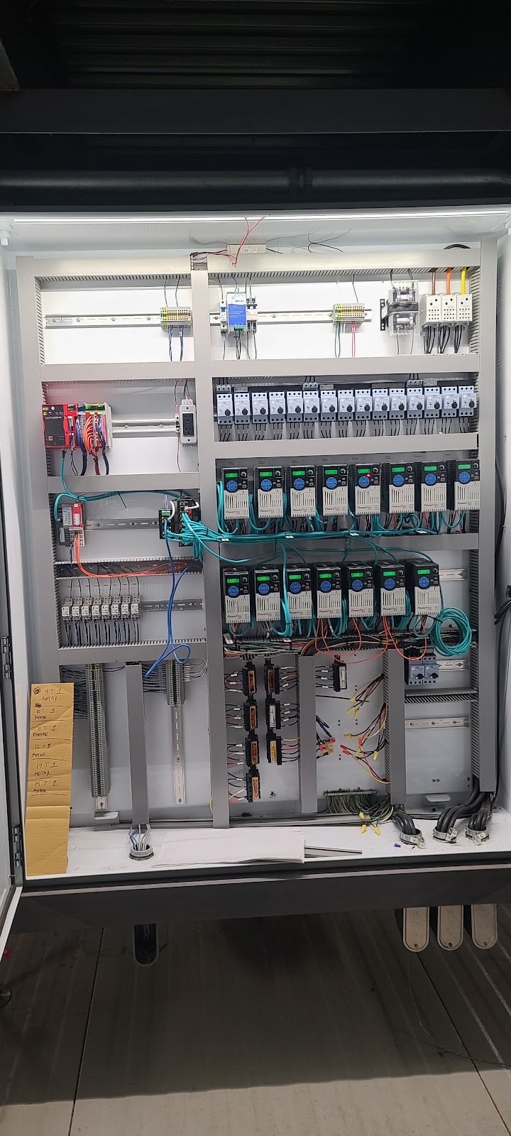 Tall open cabinet packed with PLC modules, terminals, and wiring.
