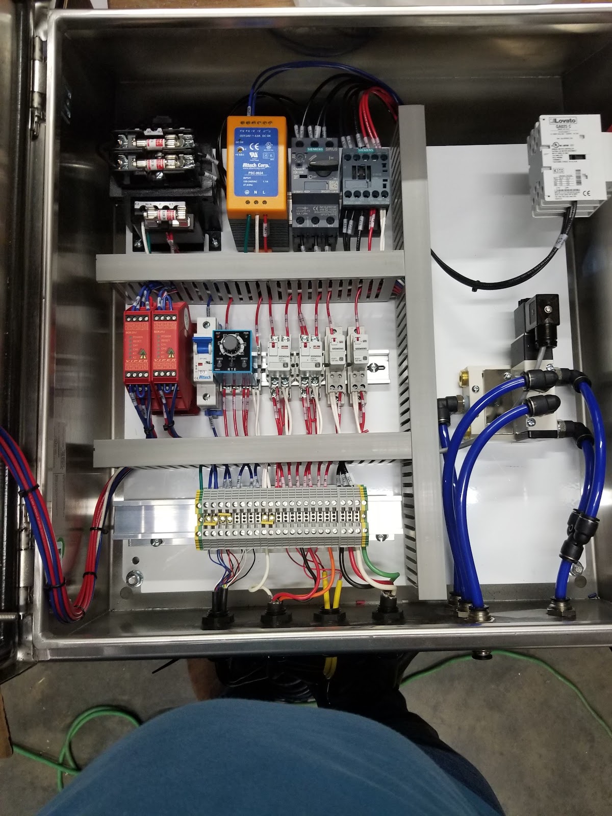 Open cabinet with a compact controller, relays, and labeled wiring.