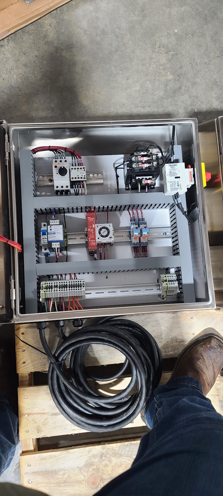 Top-down view into a stainless box with an assembly and cable coil.