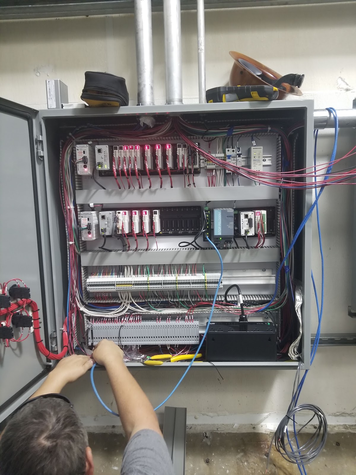Shop staff working inside a large open control cabinet.