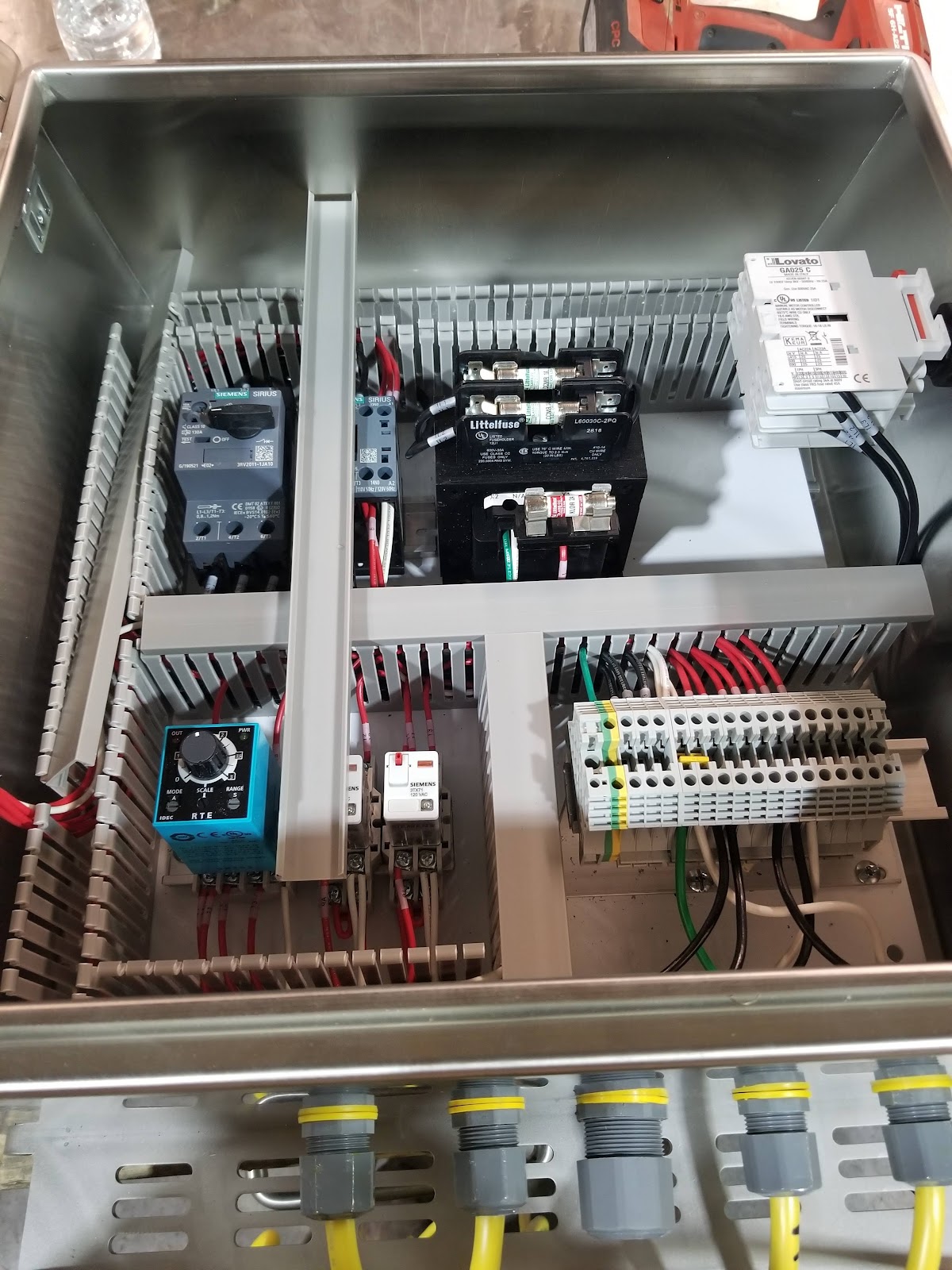 Small enclosure with a compact PLC, relay, and terminal strips.