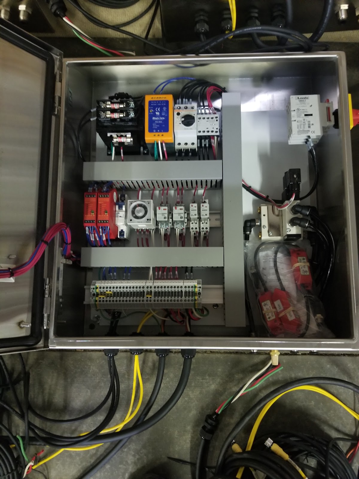 Small open control box with PLC, breakers, and clean wiring.