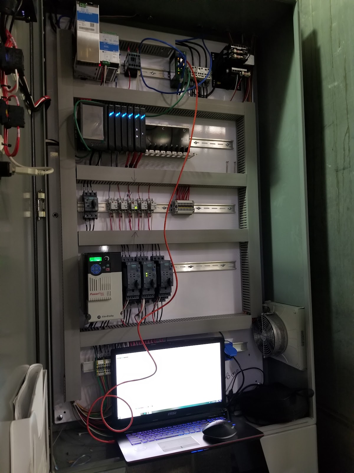 Open panel in the shop with a programming laptop connected to the hardware.