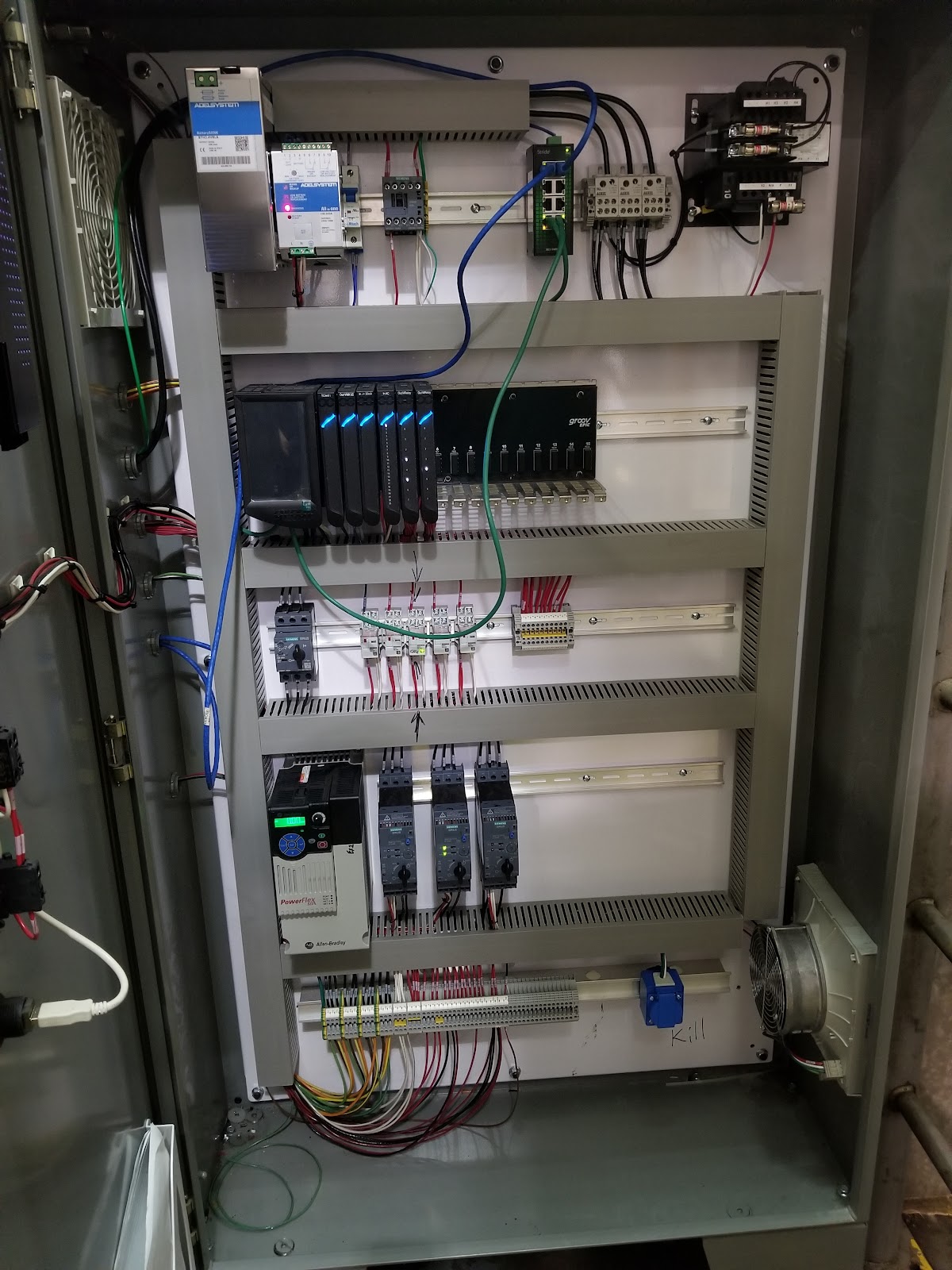 Control cabinet interior with DIN-rail hardware, wire duct, and a cooling fan.