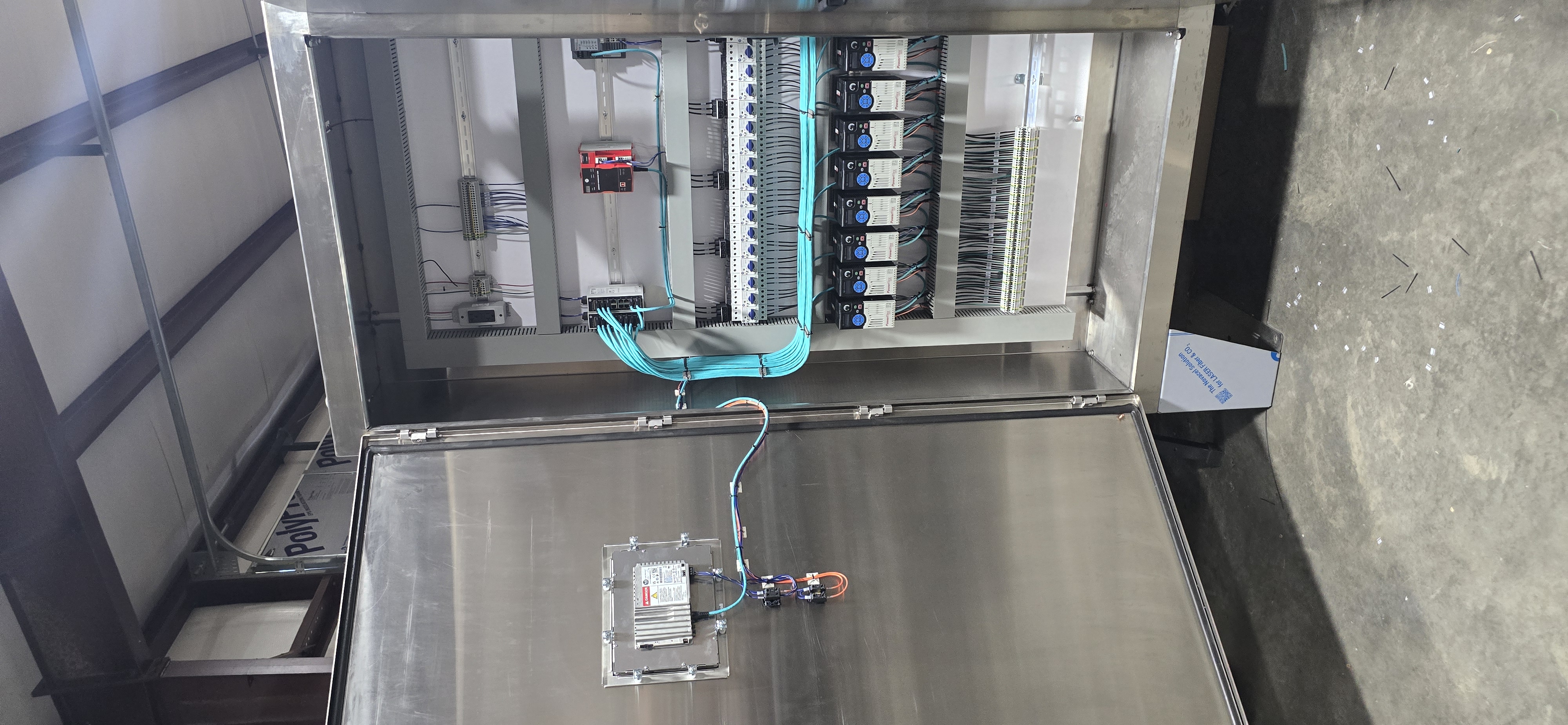 Tall stainless cabinet with circuit breakers, VFDs, and a thick blue wire bundle.